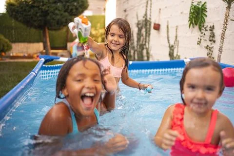 Children having fun in a backyard pool on a sunny afternoon Stock Photos