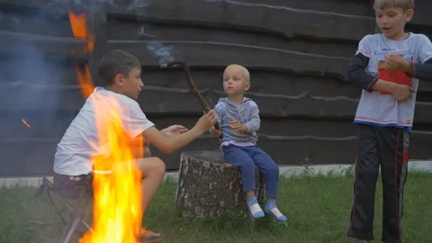 Children having fun at camp fire and playing with smoking stick Stock Footage 155516586