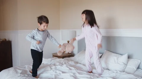 Children Having Fun Jumping And Playing On Parents Bed At Home Stock Footage 114299079