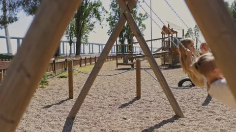 Children having fun on a swing set in a playground Stock Footage 312884156