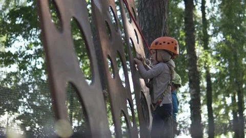 Children in helmets pass the obstacle course in the amusement park in the summer Video stock 135312505