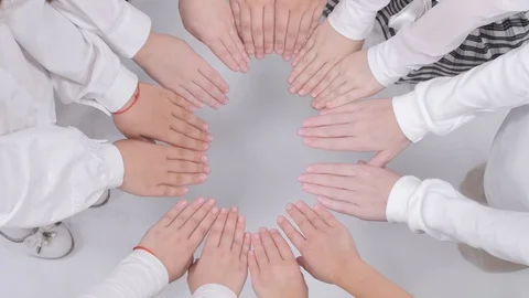 Children hold their hands in a circle and lower them on a white background. Video stock 129571908