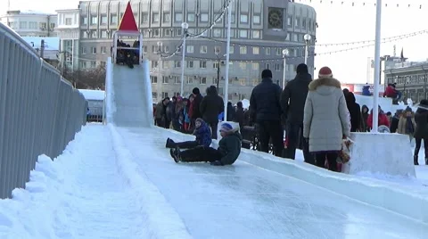 CHILDREN IN ICE TOWN MOVE DOWN FROM ICE SLIDE. CHELYABINSK, RUSSIA. Stock Footage 59868454