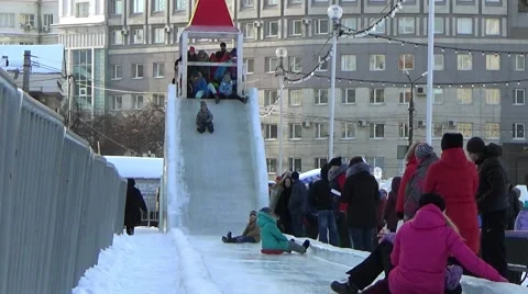 CHILDREN IN ICE TOWN MOVE DOWN FROM ICE SLIDE. CHELYABINSK, RUSSIA. 2 Stock Footage 59868475