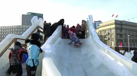 CHILDREN IN ICE TOWN MOVE DOWN FROM ICE SLIDE. CHELYABINSK, RUSSIA. 4 Stock Footage 59895755