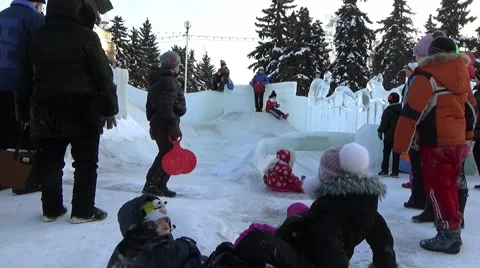 CHILDREN IN ICE TOWN MOVE DOWN FROM ICE SLIDE. CHELYABINSK, RUSSIA. 3 Stock Footage 59895836