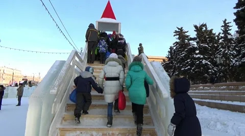 CHILDREN IN ICE TOWN MOVE DOWN FROM ICE SLIDE. CHELYABINSK, RUSSIA. 6 Stock-Footage 60364706