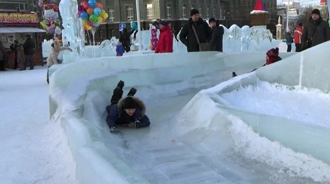 CHILDREN IN ICE TOWN MOVE DOWN FROM ICE SLIDE. CHELYABINSK, RUSSIA. 7 Stock Footage 60387290