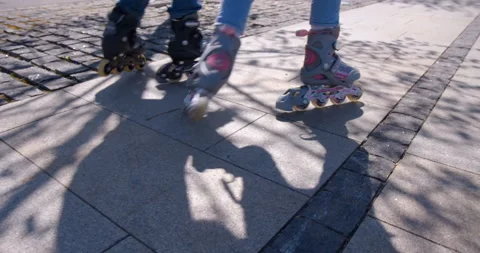 Children inline skating ride together on stone paved sidewalk Stock Footage 119565326
