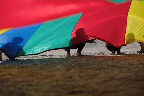 Children install a large colored canopy to protect themselves from the sun on Stock Photos