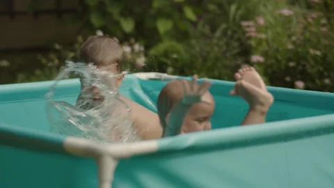 Children joyfully splash around in inflatable pool laughter echoing through the Stock Footage 275750484