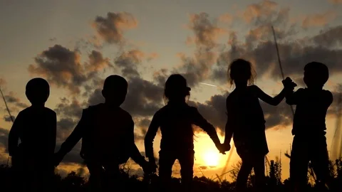 Children jump by holding hands at sunset Stock Footage