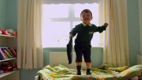 Children jumping on bed with school uniform getting ready first day at school Stock Footage