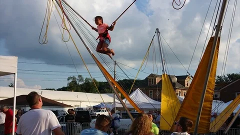 Children jumping on bungee jumping trampoline at the summer festival Stock Footage