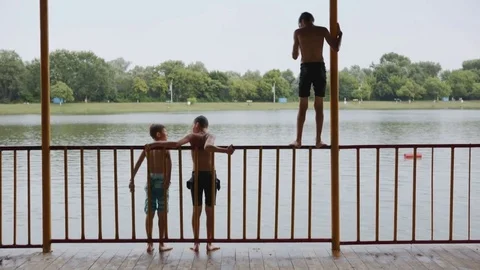 Children jumping from waterfront Stock Footage 77565116