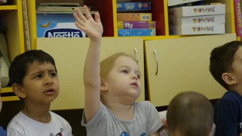 Children at kindergarten sitting on the bench and listening a teacher. Stock Footage 134013131