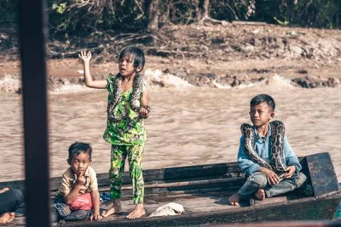 Children with large python snakes on the wooden boat at the Tonle Sap lake in 写真素材