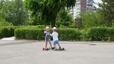 Children learn to ride scooter in a park on sunny summer day. Stock Footage 132353607
