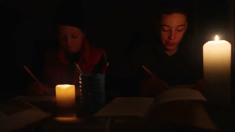 Children learning lessons in the dark. A child does school work when there is no Stock Footage 228843979