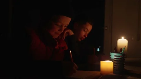 Children learning lessons in the dark. A child does school work when there is no Vídeos de archivo 228999143