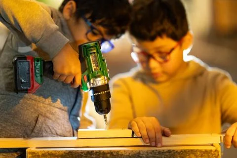 Children learning woodworking using cordless drill on wood Foto stock