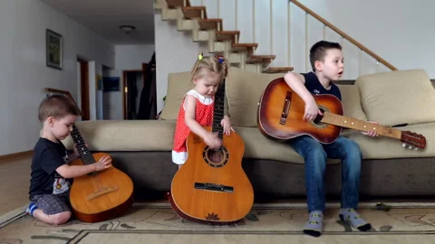 Children learns to play the classical guitar. Group of small kids playing music Vidéo 169468218