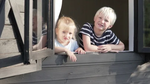 Children look out of the window of the cottage at the site and wave their hand Stock Footage 120062967