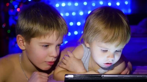 Children look at the plate lying on the bed. In the background, lights and Video stock 70816150