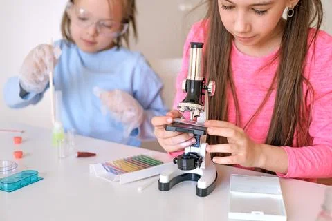 Children look at the structure of the particles of objects under a microscope Stock Photos