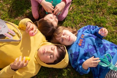 Children lying on grass celebrating easter with eggs Stock-Fotos