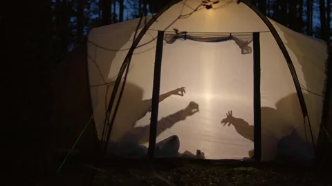 Children making shadow puppets in a camping tent at night Stock Footage 282046054
