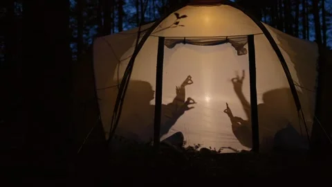 Children making shadow puppets in a camping tent at night 스톡 동영상 282596016