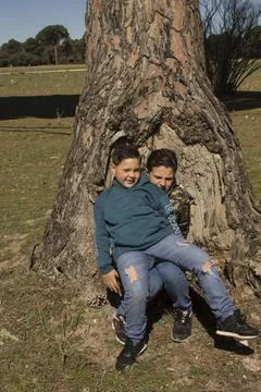Children next to a tree trunk. Stock-Fotos