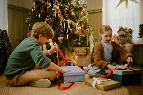 Children Opening Christmas Present Boxes near Decorated Tree Stock Photos