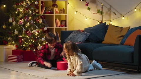 Children opening present box, playing with toy in living room. Brother and Stock Footage 165226447