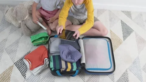 Children pack a suitcase with things to go on vacation Stock Footage 134678589