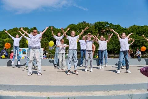 Children performing group dance outdoors under sunny summer sky Stock Photos