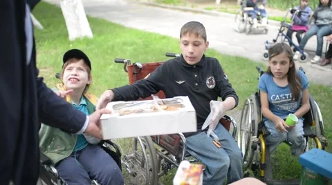 Children with physical development disorders on wheelchairs eating cookies Stock Footage 63807202