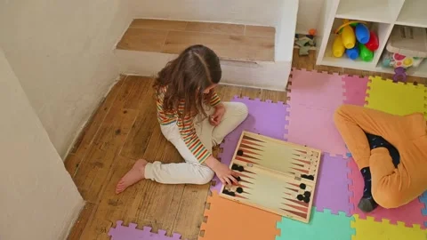 Children play backgammon on colorful foam mat in playroom Stockbeeldmateriaal 290053048