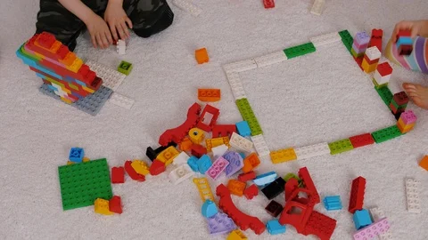 Children play colorful plastic constructor sitting on a carpet in kindergarten Video stock 124113364