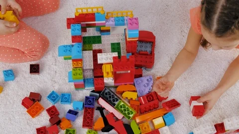 Children play colorful plastic constructor sitting on a carpet in kindergarten Stock Footage 124113485