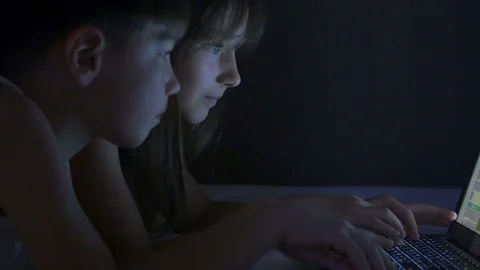 Children play on the computer in the bed under the blanket at night. Stock Footage 77170723