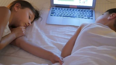 Children play on the computer in the bed under the blanket at night. Stock Footage 77579555