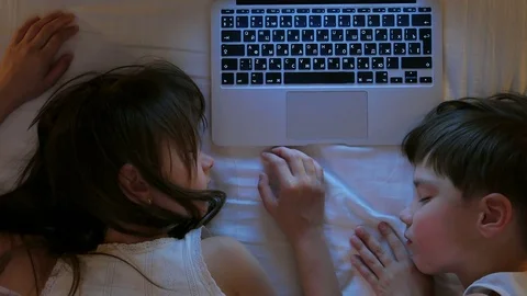 Children play on the computer in the bed under the blanket at night.  Stock Footage 77583030