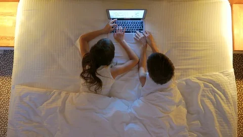 Children play on the computer in the bed under the blanket at night.  Stock Footage 77583034