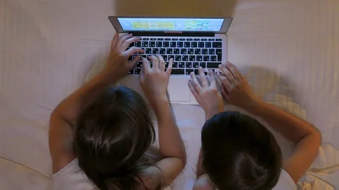 Children play on the computer in the bed under the blanket at night. Stock Footage 77583158