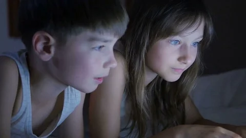 Children play on the computer in the bed under the blanket at night. Stock Footage 80424211