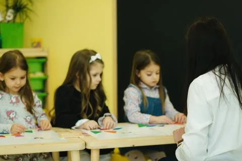 Children play with different figures on the table. Girls and boys in Stock Photos