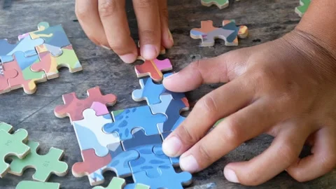 Children play jigsaw puzzles on the table. Stock Footage 310123383