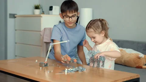 Children play with a metal constructor at the table at home. Stock Footage 239375189